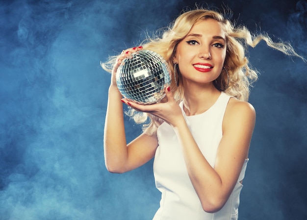Фото Красивая молодая женщина, держа диско-шар в ночном клубе
