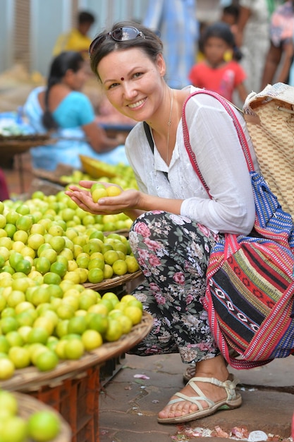 Beautiful young woman holding few lemons in hands on market