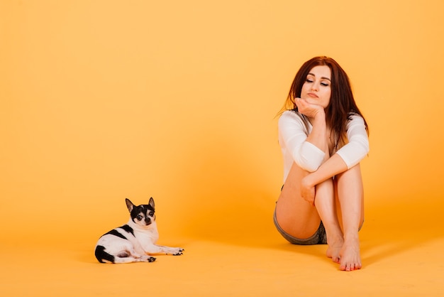 Beautiful young woman holding her dog on a yellow.