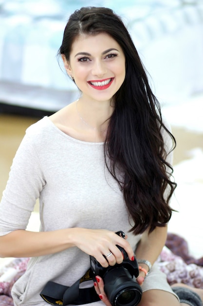 Beautiful young woman holding a professional camera in her hands