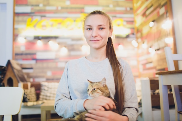 Beautiful young woman holding a red cat.