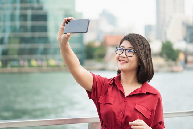 Beautiful young woman holding a smartphone. In order to take a picture of yourself 