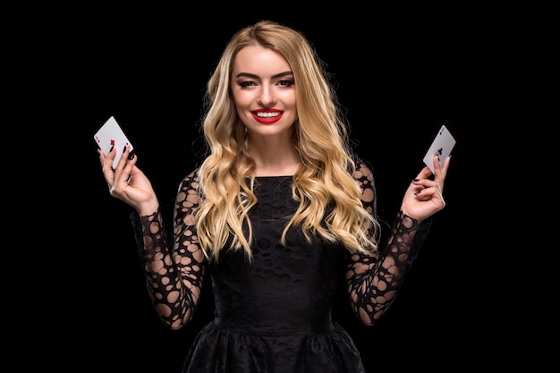 검은 배경에 고립 된 그녀의 손에 두 개의 에이스 카드를 들고 있는 아름 다운 젊은 여자