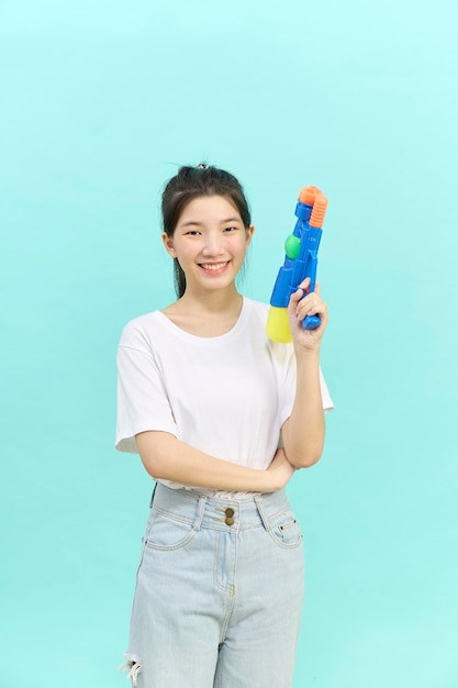 Beautiful young woman holding water gun at Songkran festival Thailand Isolated on blue background.