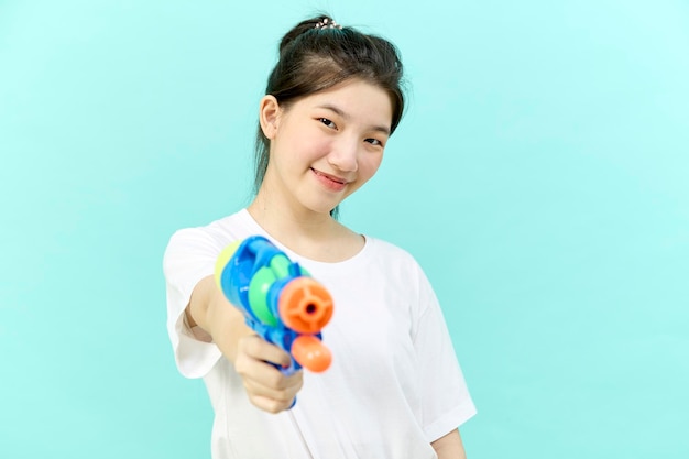 Beautiful young woman holding water gun at Songkran festival Thailand Isolated on blue background.