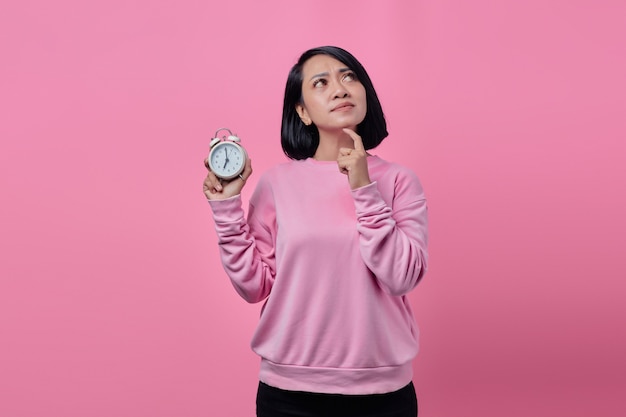 Beautiful Young woman holds white alarm clock in hand