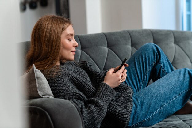 自宅で携帯電話を使って室内にいる美しい若い女性。