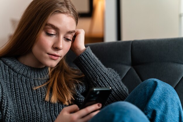 自宅で携帯電話を使って室内にいる美しい若い女性。