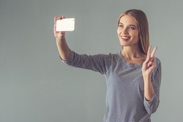 Beautiful young woman is doing selfie using a smart phone.