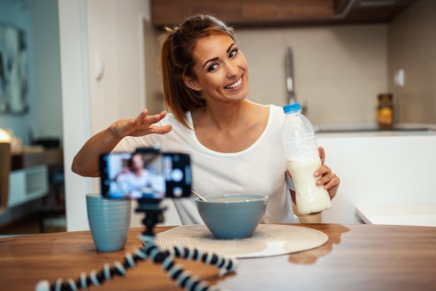 Beautiful young woman is filming her blog broadcast about healthy food at home.