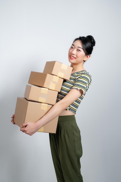 Beautiful young woman is holding cardboard box on gray background