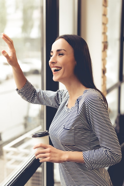 Beautiful young woman is holding a cup of coffee