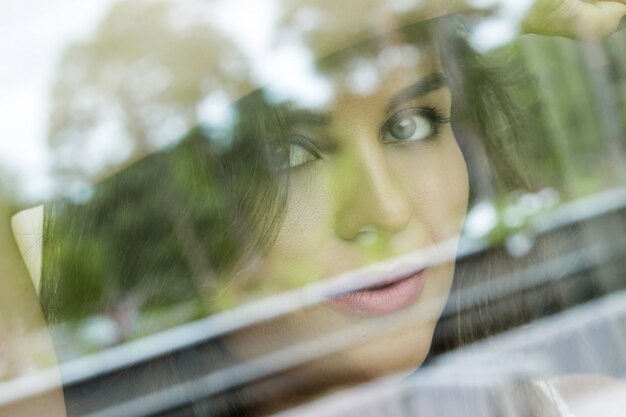 Фото Красивая молодая женщина смотрит через оконное стекло