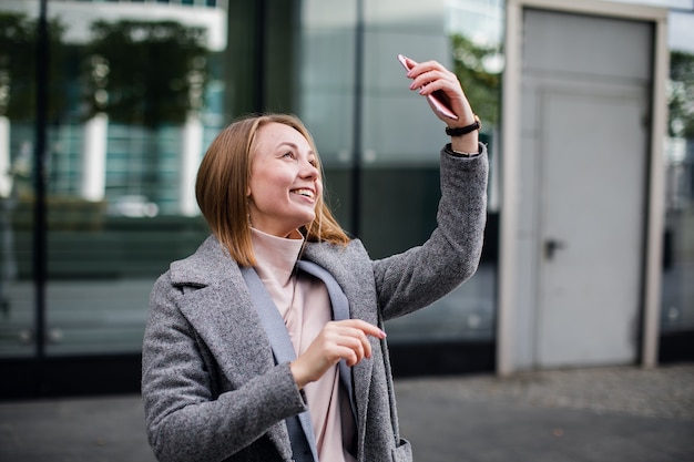 Beautiful young woman is making selfie photo with smartphone.