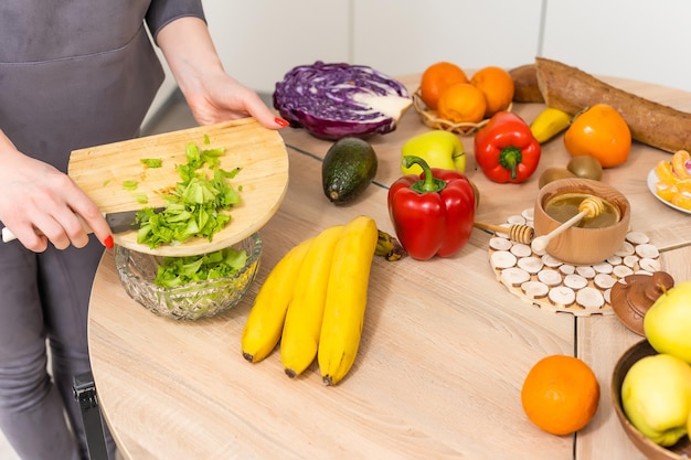 美しい若い女性が台所で野菜サラダを準備しています。家庭での料理。