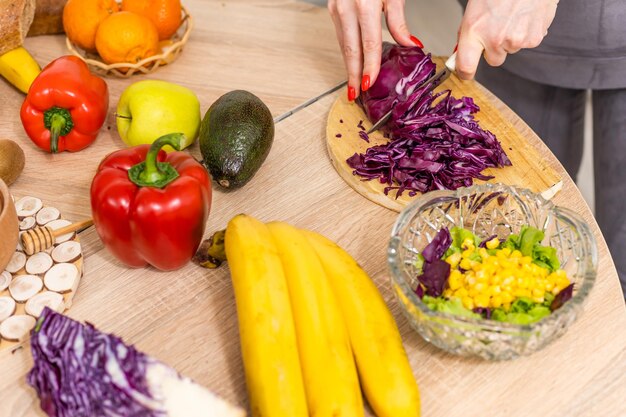 Beautiful young woman is preparing vegetable salad in the kitchen. Cooking At Home.