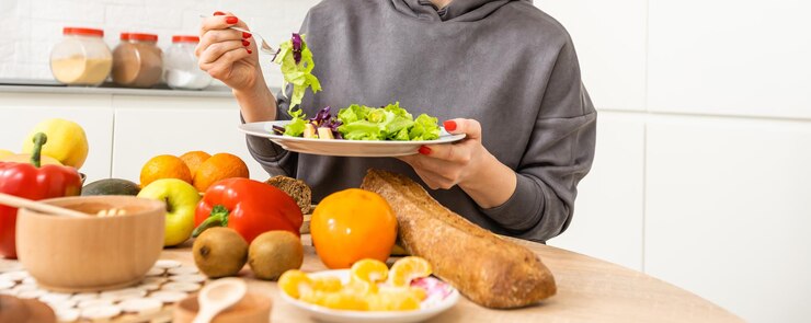 Beautiful young woman is preparing vegetable salad in the kitchen. Cooking At Home.