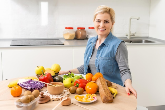 Beautiful young woman is preparing vegetable salad in the kitchen. Cooking At Home.