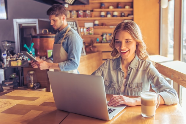 Beautiful young woman is smiling while working with laptop.