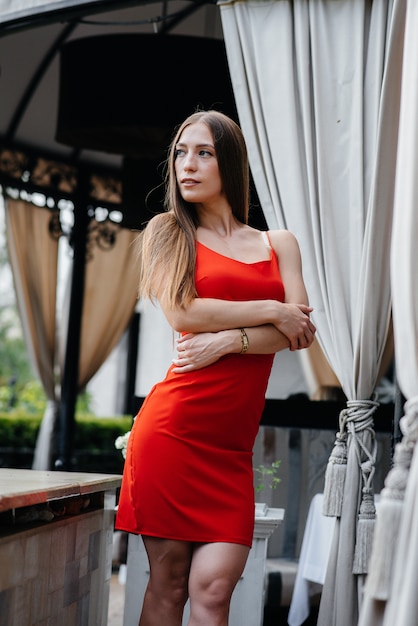 A beautiful young woman is standing on the veranda of a beautiful house.