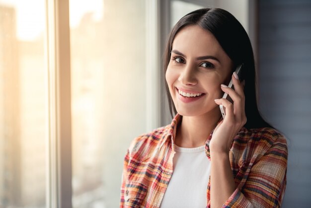 美しい若い女性は携帯電話で話しています。