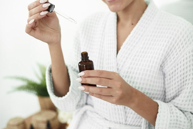 Beautiful Young Woman is Using Moisturizer Anti-Aging Serum Treatment on Her Hands. Beauty Body Skin Care and Cosmetic Apply Concept.