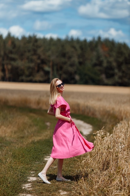 A beautiful young woman is walking in a wheat field.