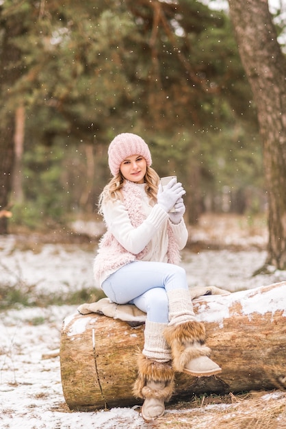 Beautiful young woman in jeans and pink jacket in winter forest