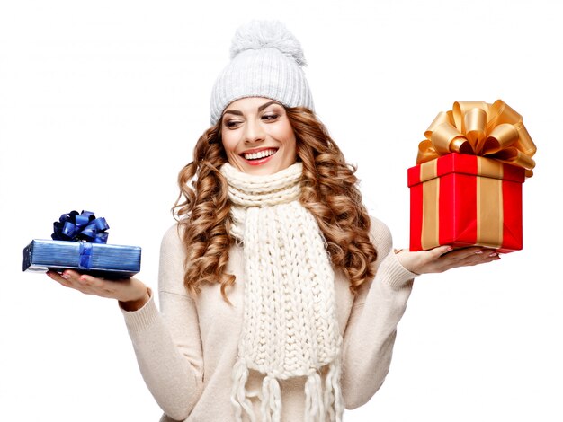 Beautiful young woman in knitted woolen sweater smiling holding gift boxes