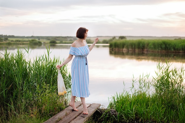 日没時の湖の美しい若い女性