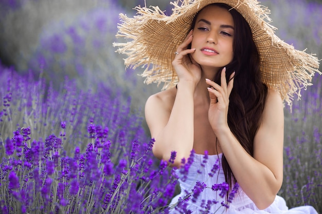 Beautiful young woman on lavender field. Aroma concept. Attractive young female outdoors.