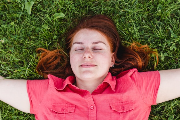 Beautiful young woman lies on the grass. Fresh natural summer concept. View from the top.