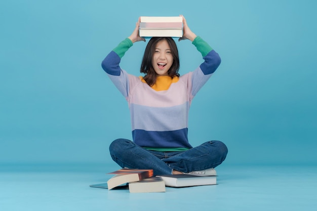 Una bella giovane donna solleva molti libri sulla testa mentre sorride felice