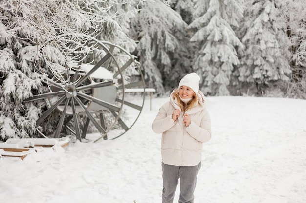 Beautiful young woman in light warm cozy clothes walks in snowy forest Stylish model with beautiful smile Winter vacation