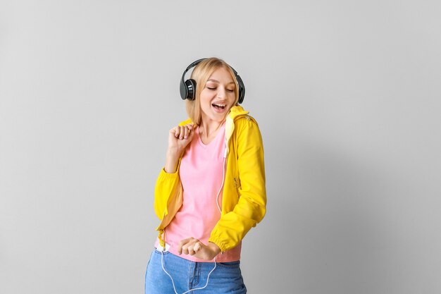 Beautiful young woman listening to music on light