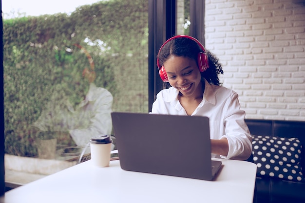 Beautiful young woman listening to music with headphones and drinking coffee in a cafe