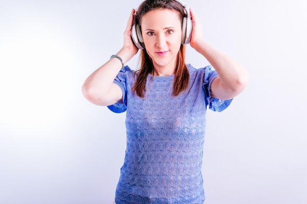 Beautiful young woman listening to music with headphones on white background