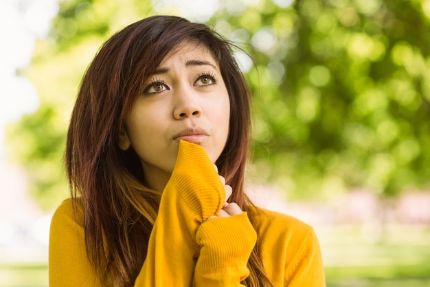 公園で遠くを見ている美しい若い女性