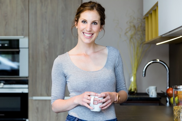 Beautiful young woman looking at camera in the kitchen at home.