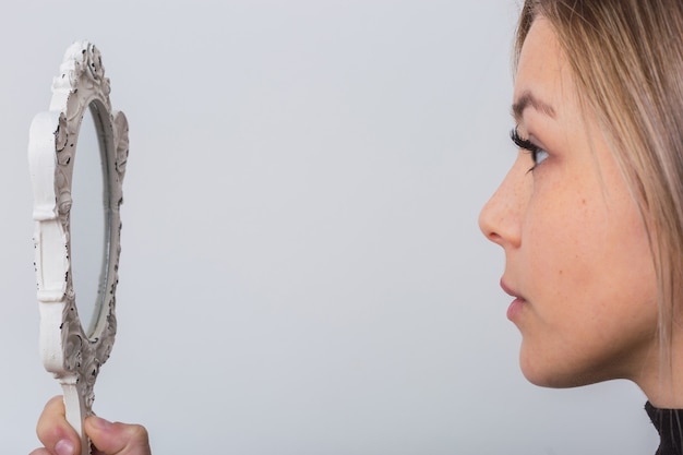 Bella giovane donna che guarda se stessa in uno specchio