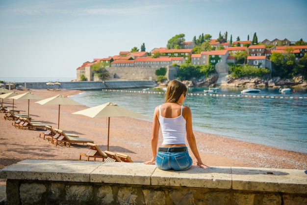 바다와 섬 Sveti Stefan보고 아름 다운 젊은 여자. 몬테네그로, 유럽.