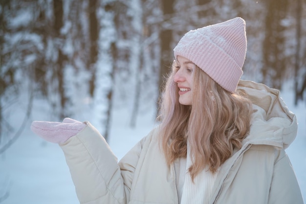 사진 아름 다운 젊은 여자는 아름 다운 겨울 공원에서 장갑에 손바닥을 살펴봅니다. 광고를 위한 공백