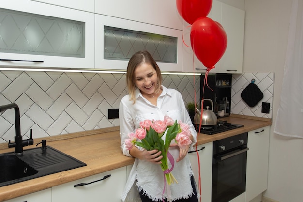 Beautiful young woman looks at the flowers presented to her and smiles Heartshaped balls