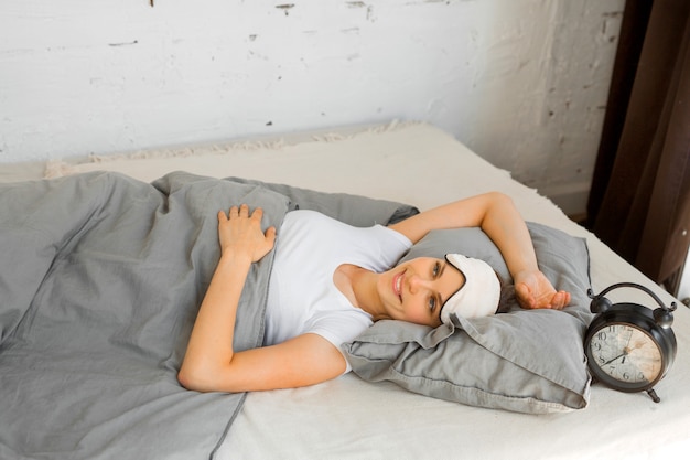 beautiful young woman lying in bed at home under the covers