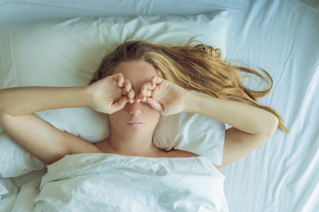 Beautiful young woman lying down in bed and sleeping. Do not get enough sleep concept