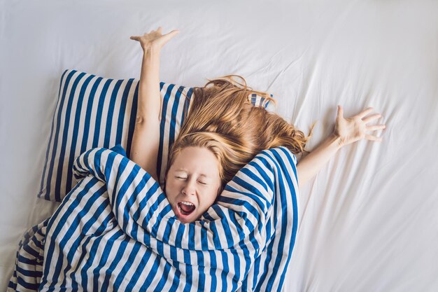 Beautiful young woman lying down in bed and sleeping. Do not get enough sleep concept