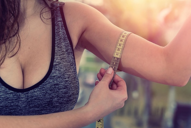 beautiful young woman makes measurements with a tape of her body after a workout in the gym. Sport concept. The concept of body size and weight