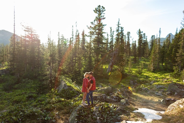 Beautiful young woman and man walk hug and kiss in mountain nature at sunse