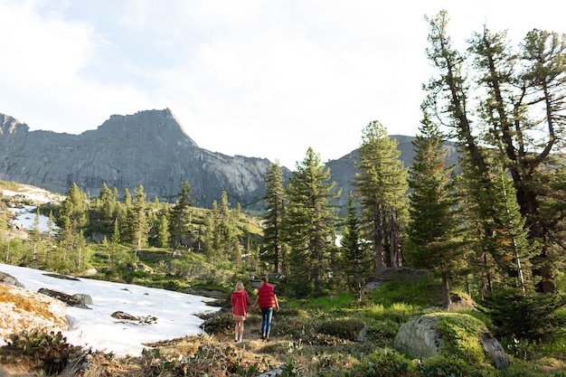 Beautiful young woman and man walk hug and kiss in mountain nature at sunse