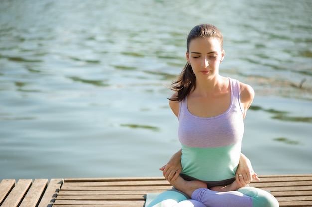 Beautiful young woman meditating in yoga pose at a mountain stream